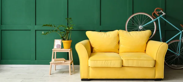 Yellow sofa and bicycle near green wall