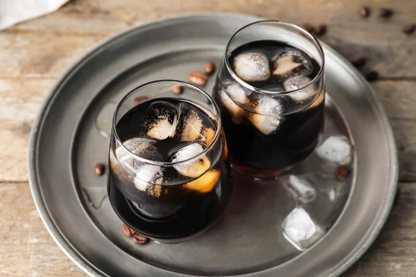 Plate with glasses of cold brew coffee on wooden table