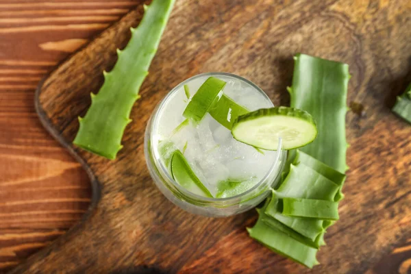 Glass of aloe juice with cucumber on wooden background, closeup