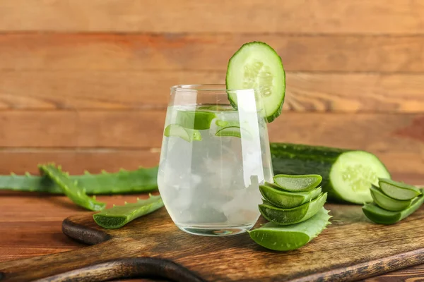 Glass of aloe juice with cucumber on wooden background