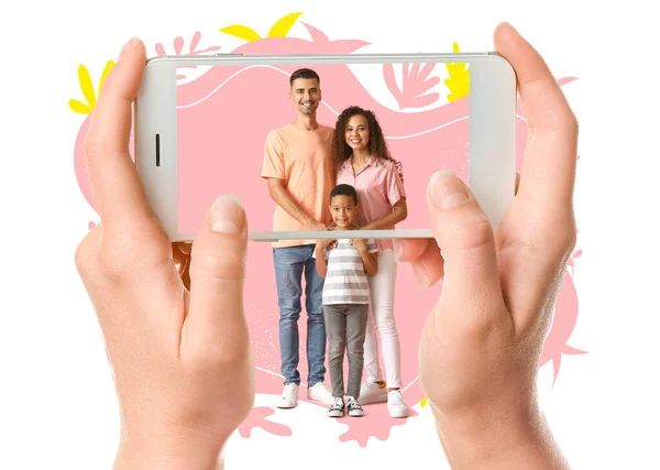 Woman with mobile phone taking photo of happy interracial family