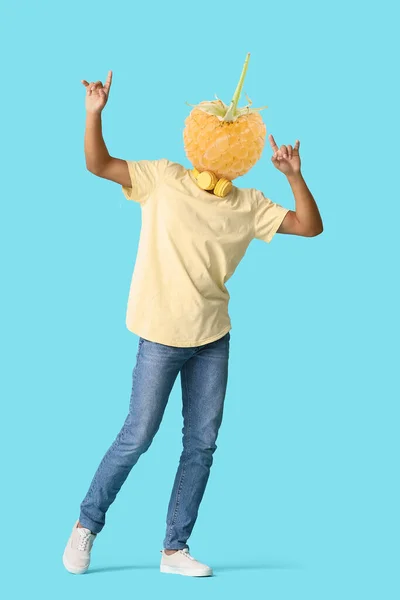 Dancing man with ripe yellow raspberry instead of his head on light blue background