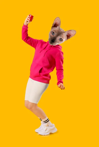 人間の体と黄色の背景で踊るワイヤレスポータブルスピーカーとスフィンクス猫 — ストック写真