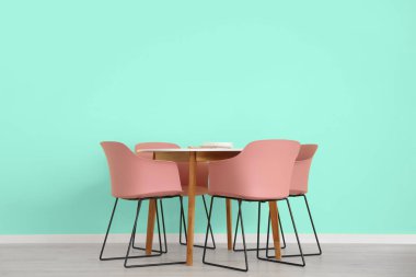 Yemek masası ve nane duvarının yanındaki sandalyeler.