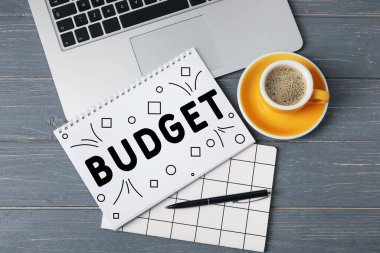 Dizüstü bilgisayar, defterler, bir fincan kahve ve tahta arka planda bir kalem. Planlama bütçesi kavramı