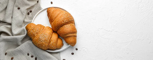 Plate with tasty croissants on white table. Banner for design