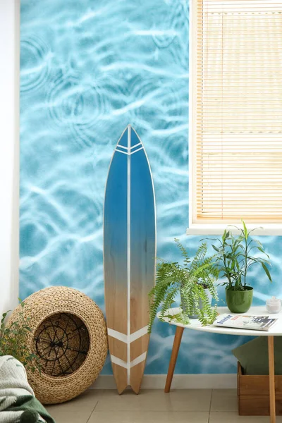 带有冲浪板的现代时尚房间内及墙壁附近的桌子 上面印着清澈的蓝水 — 图库照片