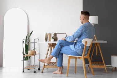 Genç çıplak ayaklı adam evde dizüstü bilgisayar kullanıyor.