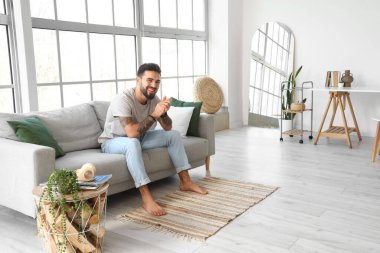 Evdeki kanepede oturan yakışıklı çıplak ayaklı adam.