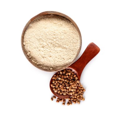 Beyaz zemin üzerinde karabuğday taneleri olan bir kase un ve kaşık.