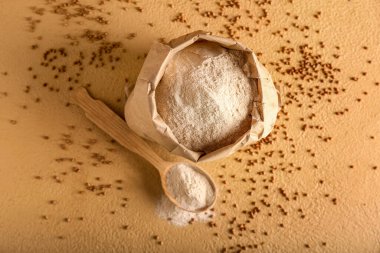 Üzerinde un, kaşık ve karabuğday taneleri olan kağıt torba.