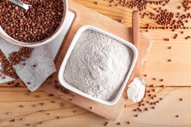 Tahtada un ve ahşap arka planda karabuğday taneleri var.