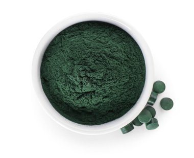 Bir kase spirulina tozu ve beyaz arka planda haplar.