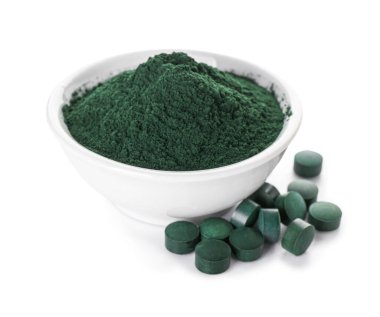 Bir kase spirulina tozu ve beyaz arka planda haplar.
