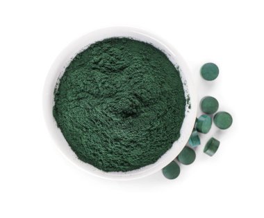 Bir kase spirulina tozu ve beyaz arka planda haplar.