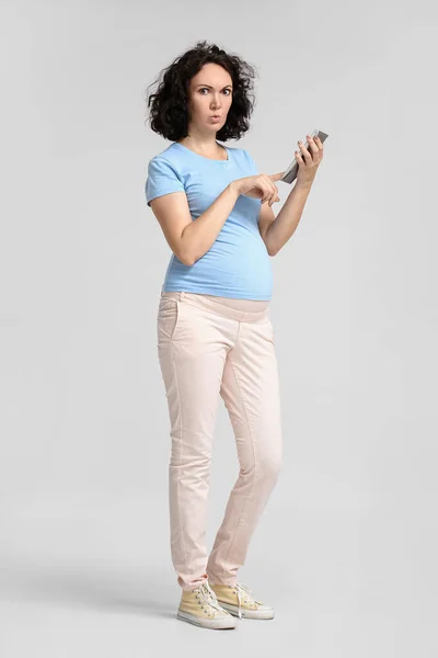 Mujer Embarazada Joven Trastornada Usando Calculadora Sobre Fondo Claro —  Fotos de Stock