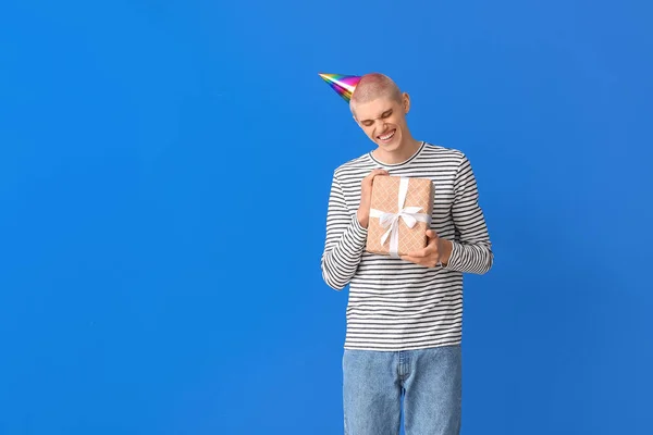 若いです男でパーティー帽子でプレゼント上の青の背景 — ストック写真