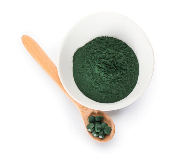 Чаша спирулина порошок и ложка с таблетками на белом фоне