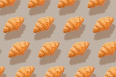 Gri arka planda bir sürü taze kruvasan var. Tasarım için desen