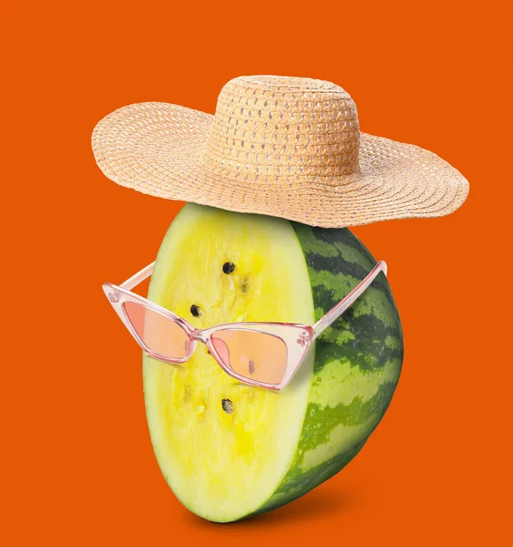 Funny yellow watermelon wearing sunglasses and hat on orange background