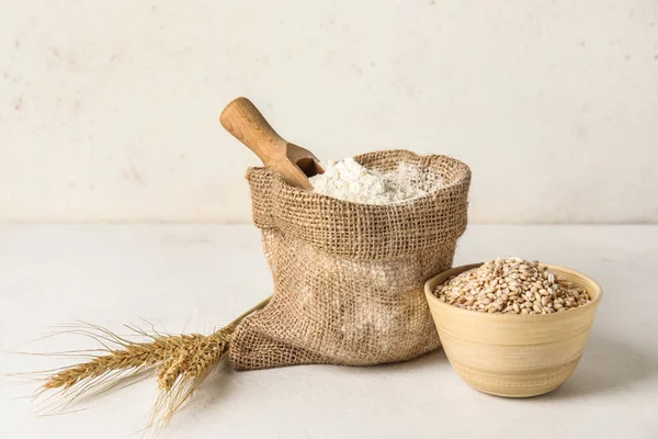 装面粉的袋子和浅色背景的小麦碗 — 图库照片