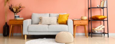 Kanepesi, ahşap masaları, puf ve raf ünitesi olan şık bir oturma odası.