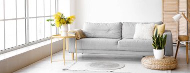 Pencerenin yanında kanepesi ve masası olan modern oturma odası.