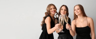 Güzel genç kadınlar açık arkaplanda şampanya içerken mesaj için yer açıyorlar.