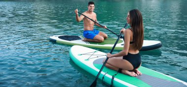 Genç çift nehirde sörf yapmak için sörf tahtası kullanıyor.