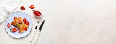 Açık arkaplanda çilekli, reçelli ve çatal bıçaklı ince gözleme tabağı.