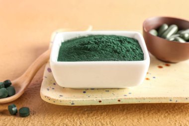 Bej arka planda bir kase spirulina tozu, yakın plan.