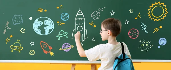 Little boy drawing space on school blackboard