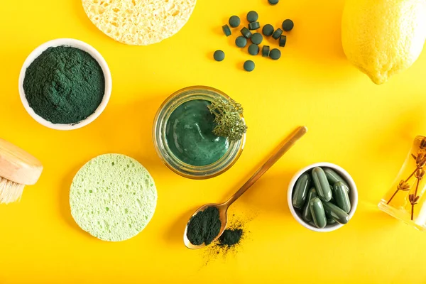 Composition with spirulina facial mask, ingredients and sponges on yellow background