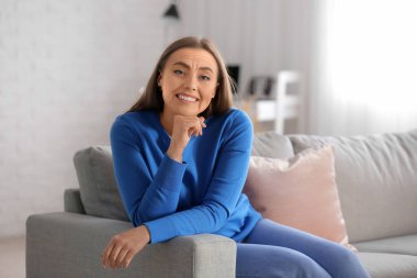 Evdeki kanepede oturan mutlu yaşlı kadın. Yaşlanma süreci