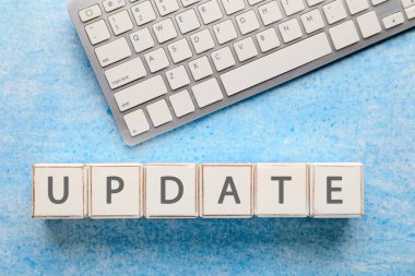 Açık mavi arkaplanda küp ve PC klavyeden oluşan kelime UPDATE