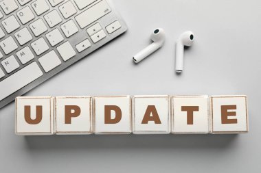 Küpler, PC klavye ve hafif arkaplanda kulaklıklardan oluşan kelime UPDATE