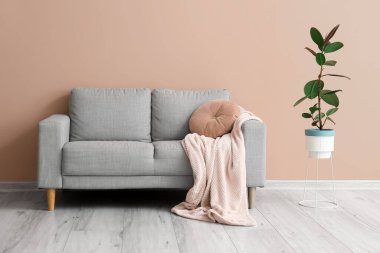 Bej duvarın yanında ekoseli ve çiçekli kanepe.