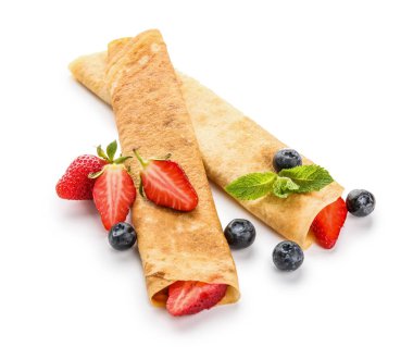 Beyaz arka planda çilek ve nane yapraklı lezzetli ince krepler.