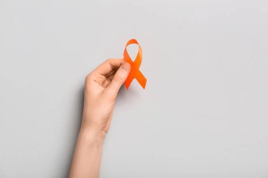 Gri arka planda turuncu farkındalık kurdelesi olan bir kadın. Böbrek kanseri kavramı
