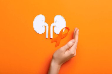 Turuncu arka planda kurdeleli ve kağıt böbrekli bir kadın.