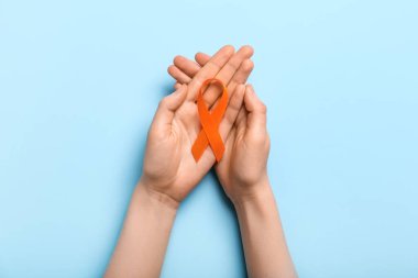 Mavi arka planda turuncu farkındalık kurdelesi olan bir kadın. Böbrek kanseri kavramı