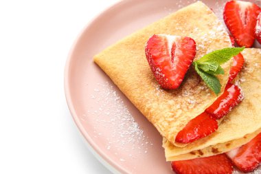 Beyaz arka planda çilek ve nane yapraklı ince krep tabağı, yakın plan.