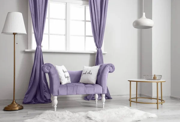 Interior of light room with purple armchair and curtains