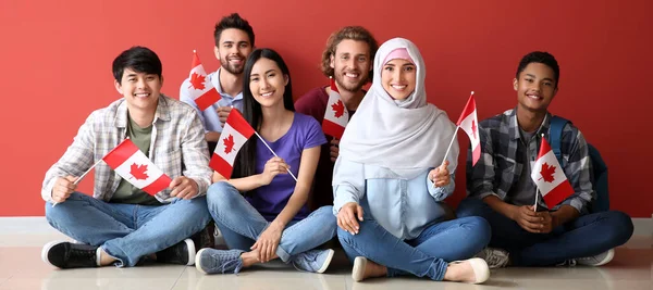 Група Студентів Канадськими Прапорами Сидять Біля Червоної Стіни — стокове фото