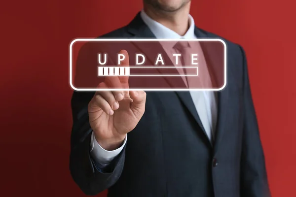Businessman touching virtual screen with word UPDATE and status bar on red background