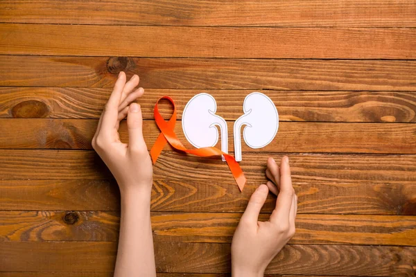 Vrouw Met Oranje Bewustzijnslint Papieren Nieren Houten Ondergrond — Stockfoto