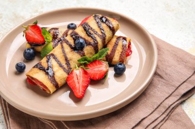 Arkaplanda böğürtlen, çikolata şurubu ve peçete olan ince krepler, yakın plan.