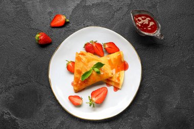 Üzerinde çilek, reçel ve nane yaprakları olan ince krep tabağı.