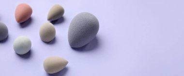 Eflatun arka planda farklı makyaj süngerleri. Tasarım için pankart