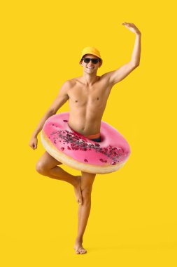 Sarı arka planda kocaman donutu olan komik bir genç adam.